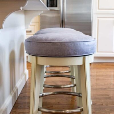 Distressed grey leather upholstered barstools by Jamie Stern